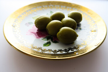 Mediterranean food, olives on a golden plate on a white background