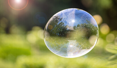 A large soap bubble flies in the park.