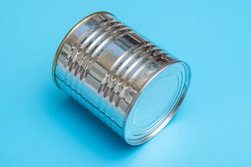 Closed metal can of canned food on a blue background.