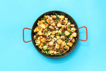 Frying pan with tasty vegetables and chicken on color background