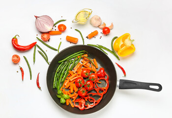Frying pan with different vegetables on white background