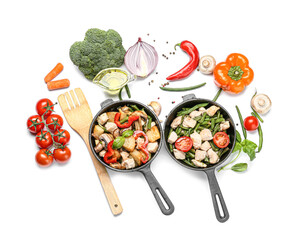 Frying pans with tasty vegetables and chicken on white background