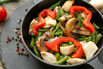 Frying pan with tasty vegetables and chicken on table, closeup