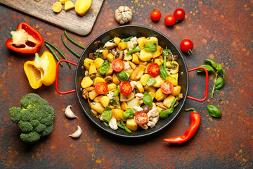 Frying pan with tasty vegetables and chicken on grunge background