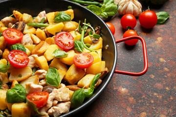 Frying pan with tasty vegetables and chicken on grunge background, closeup