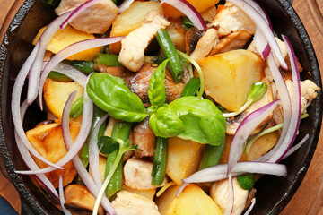 Frying pan with tasty vegetables and chicken on table, closeup