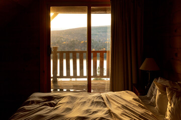 point de vue d'un lit avec vue sur l'extérieur et sur le balcon lors d'un coucher de soleil