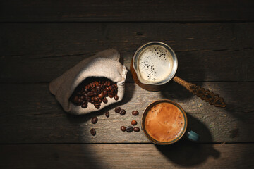 Obraz na płótnie Canvas Cup and jezve with hot coffee on dark background