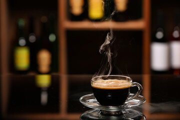 Cup with hot coffee on table against blurred background