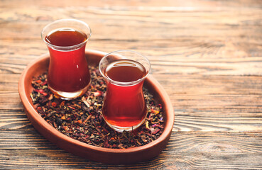 Cups with hot Turkish tea and dry leaves on wooden background