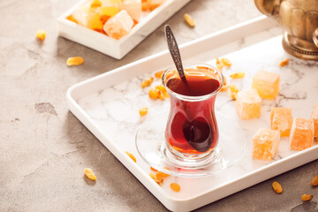 Cup with hot Turkish tea and sweets on light background