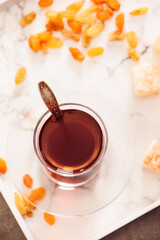 Cup with hot Turkish tea and raisins on light background