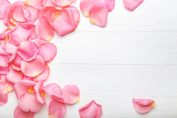 Beautiful pink rose petals on white wooden background