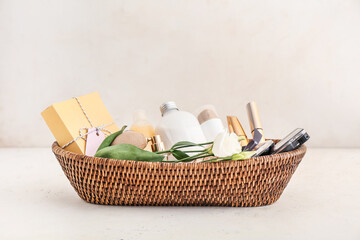 Gift basket with cosmetics on light background