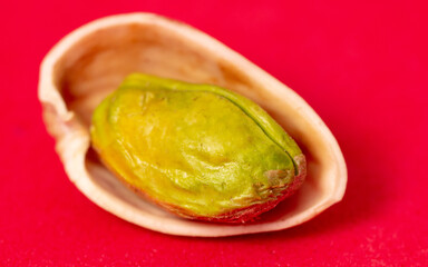 Close-up of fresh pistachio nuts on a red background.