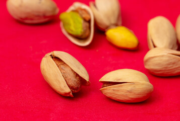Close-up of fresh pistachio nuts on a red background.