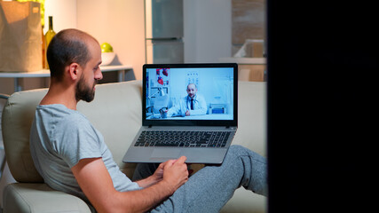 Sick man having online telemedicine consultation during covid-19. Caucasian male sitting in front of laptop disscusing with medical physician about illness symptoms working on healthcare treatment