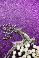 Reindeer and white berry Christmas decoration on purple glitter background