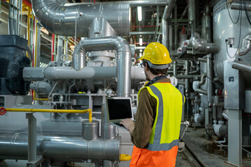 Mechanical maintenance technician inspecting pressure gauge of heating system in heating plant.