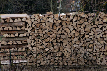 cut firewood and stapled in a row outdoor in an ornamental garden in spring