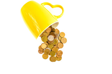 Yellow ceramic cup fell and metal coins scattered, isolated on white background. Image of metallic money. Store and protect savings. Copy space. Selective focus.