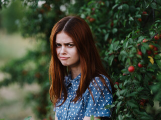 Fototapeta premium Beautiful woman near green bushes with red berries on nature in the park