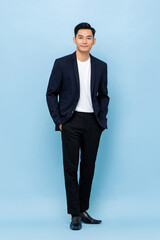 Obraz na płótnie Canvas Full length portrait of happy smiling young handsome southeast Asian businessman standing on light blue studio background