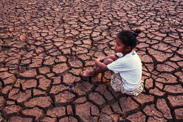A poor asian  child a drought, sorrow, sits on a dry ground, hopes and drought.