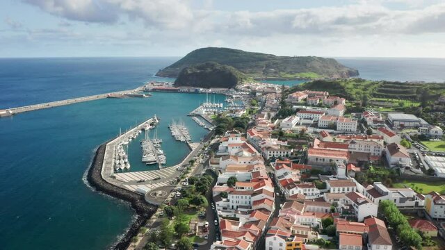 Panoramic view of Monte de Guia volcanic area and Horta city buildings, Faial Island, Azores, Portugal, Europe. Drone shot of ocean coastline with small port at Horta town, 4k footage