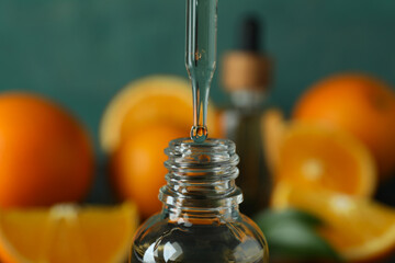 Pipette dripping oil in bottle against fresh oranges