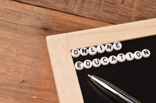 Top view of pen, chalkboard and alphabet beads with text ONLINE EDUCATION.