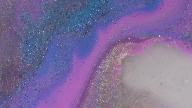 A stream of liquid pastel pink purple blue lilac pearl paints with shiny particles. Makeup texture. Abstract art painting background