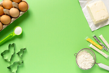 Ingredients for making easter cookies in the shape of bunny on green background, copyspace