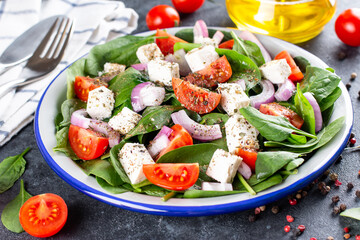 Healthy food. Greek salad with spinach, tomato, sweet pepper, red onion, feta cheese on a dark background