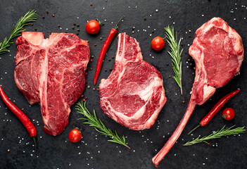 Three raw beef steaks for grilling - rib-eye steak, T-Bone steak, Tomahawk steak on stone background