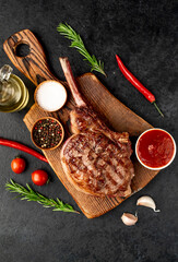 Grilled tomahawk beef steak with spices on stone background