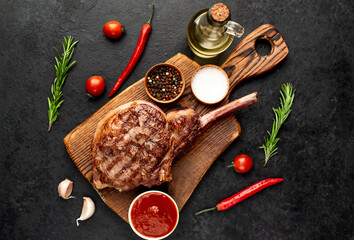 Grilled tomahawk beef steak with spices on stone background