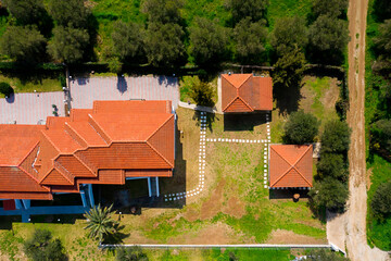 Top aerial view from above to countryside plan with red tile roofs, green trees, ground road. Yard of private residential house, cottage on grass lawn background