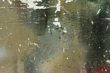 background for text with the effect of antiquity. the cracked and scratched surface of a concrete wall painted with spots of green paint.