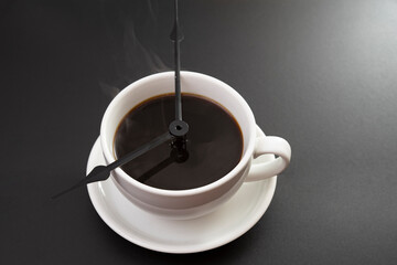 Coffee with clock tongues showing 8 o`clock isolated on black. Coffee time concept.