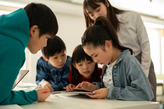 ICT in Education - Elementary School Students and Teacher Looking at Tablet PC