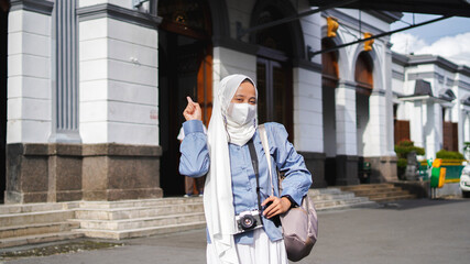 Asian women traveling by train in front of the station wearing jilbab and analog camera