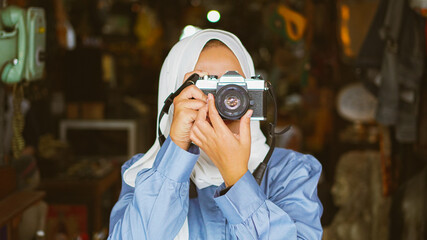 Asian women travel and visit antique shops wearing jilbab and analog camera