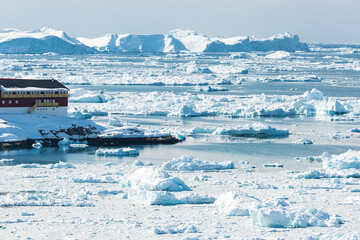 Building at Ilulissat village besides fjord with icebergs