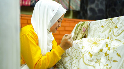 Asian women learn to make batik wearing jilbab and analog camera