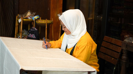 Asian women learn to make batik wearing jilbab and analog camera