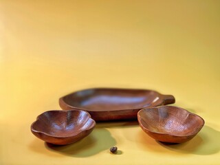 brown wooden bowls lie on the yellow background