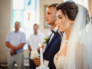 Spiritual couple holding candles during wedding ceremony in christian church, close up. The priest...