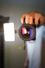 man with a camera in his hands in front of a mirror, close-up view of the lens and illumination 