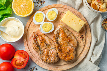 Ingredients for Caesar salad on a cutting board on a gray background.